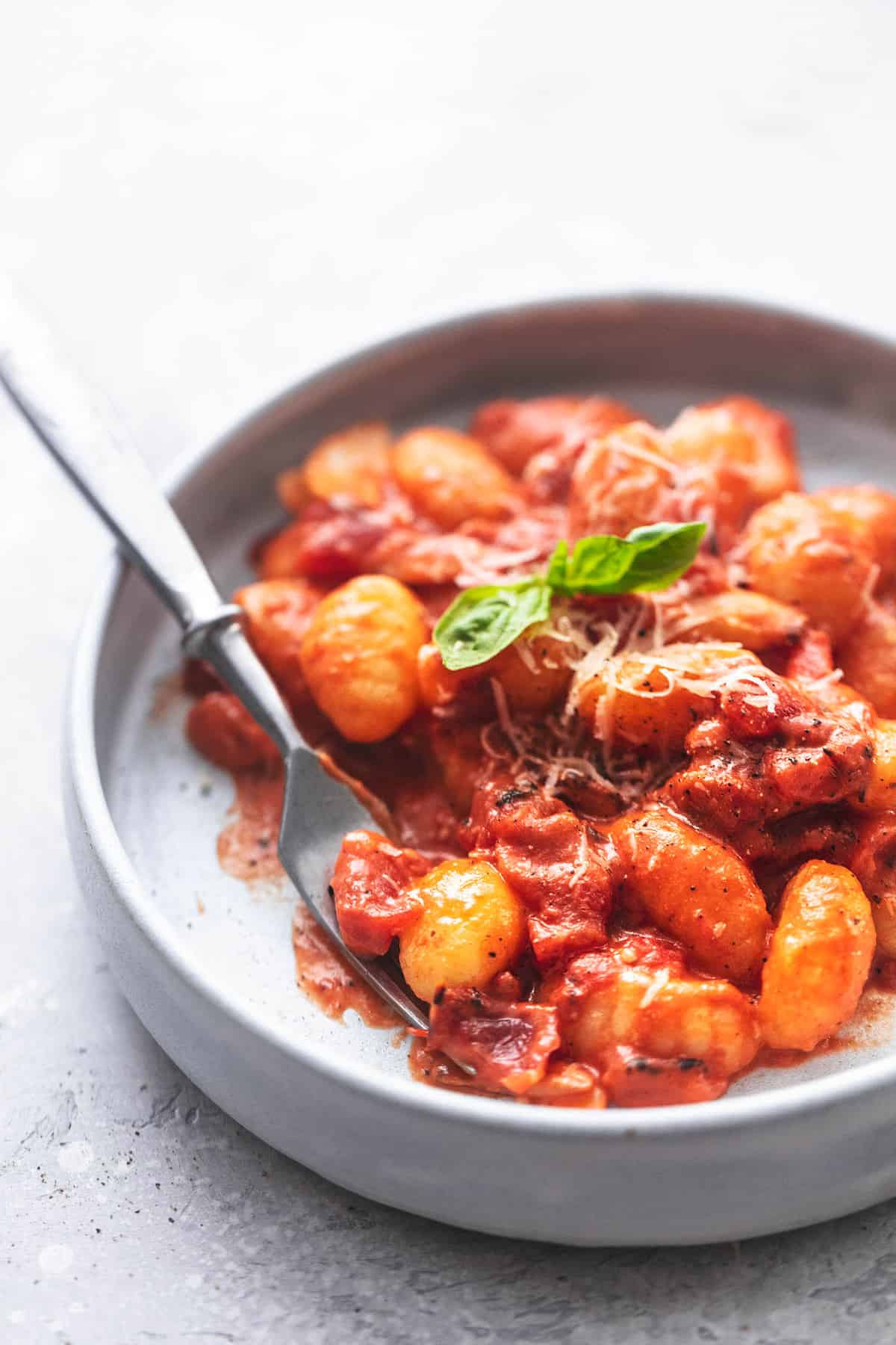 Gnocchi mit cremiger Tomatensauce auf einem grauen Teller mit einer Gabel