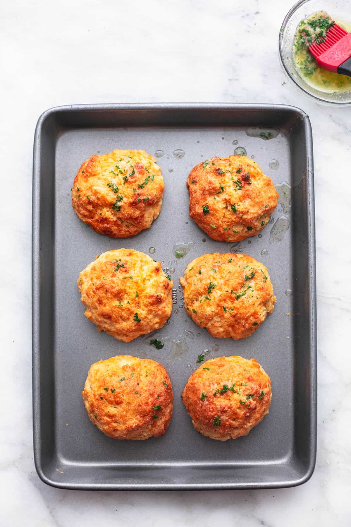 red lobster cheddar bay biscuits on a baking pan with butter sauce in a bowl